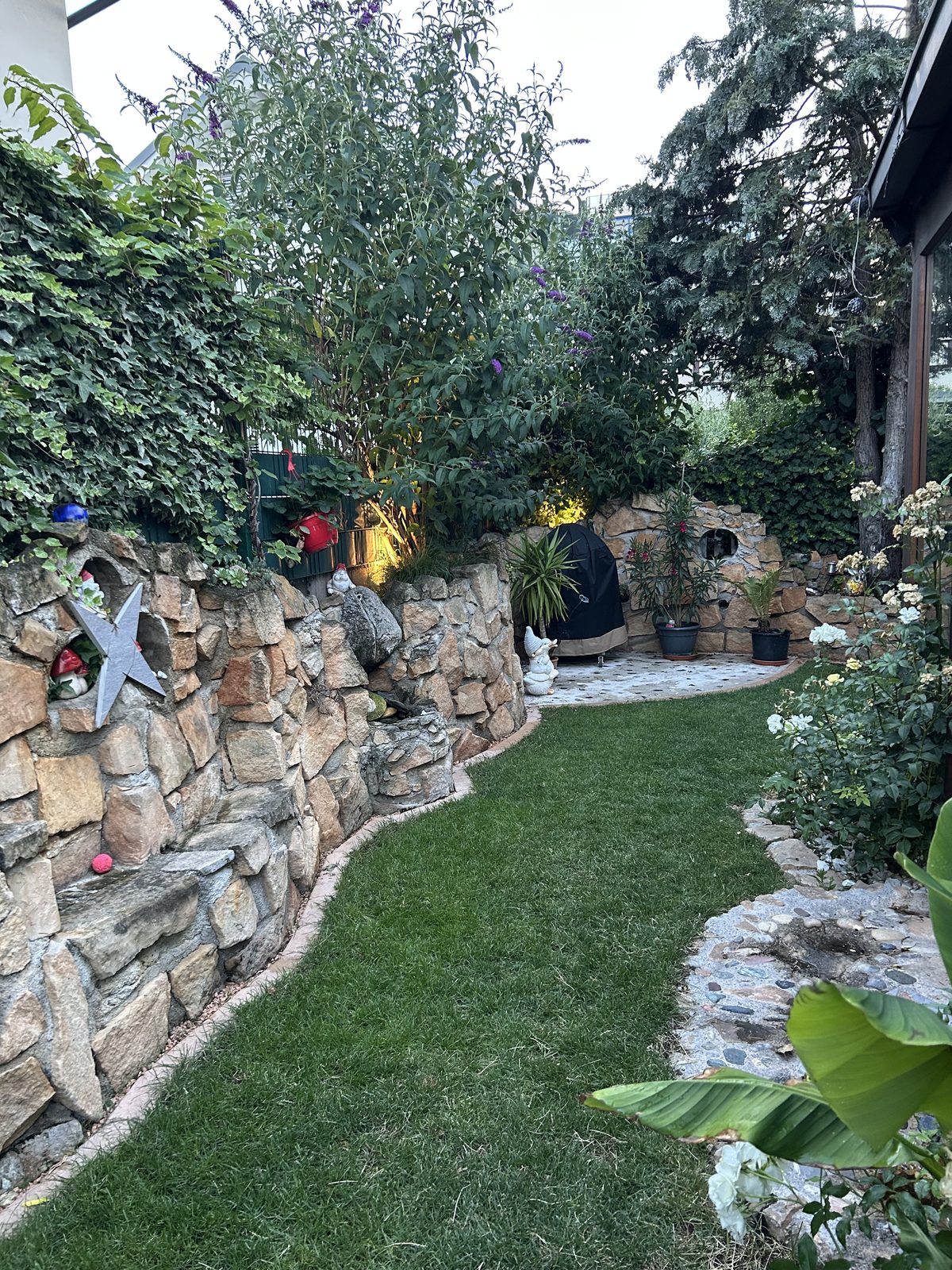 Fertiger Garten mit geschwungenem Rasen und Steinmauer